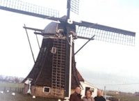 three people standing in front of a windmill