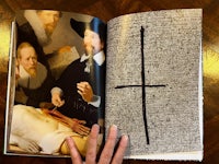 a person holding a book with a picture of a cross