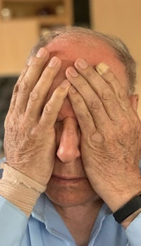 an older man covering his eyes with his hands