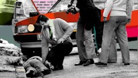 a man is laying on the ground next to a car