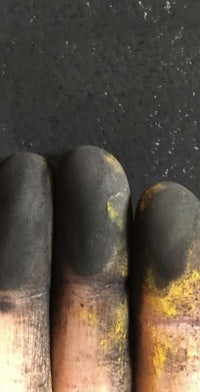 a person's finger with black and yellow paint on it