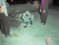 a man is laying on the ground next to a car