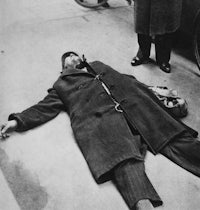 a man laying on the ground next to a car