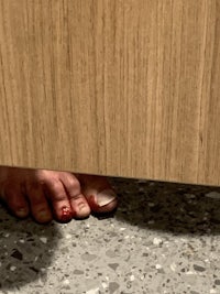 a person's foot with blood on it under a wooden floor