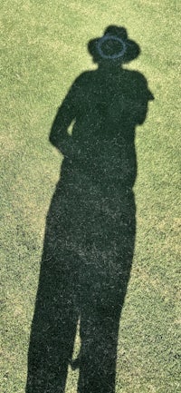 a shadow of a person standing on a grassy field