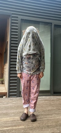 a child standing on a wooden deck with his head covered