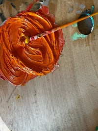 an orange paint brush on a wooden table