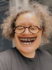 a woman with glasses and a smile on her face