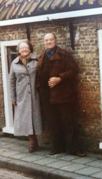 a man and woman standing in front of a brick house