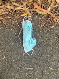 a blue surgical mask laying on the ground