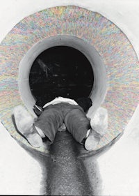 a black and white photo of a person laying in a pipe