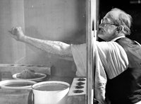 a man standing in front of a window with pots in front of him