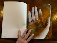 an open book with a hand holding a ring