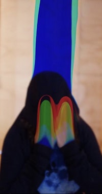 a person with a rainbow colored hat covering their face